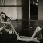 Two dancers sit on stage floor